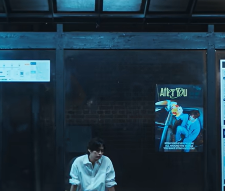 Lee Know sitting next to Seungmin poster in "After You" music video.